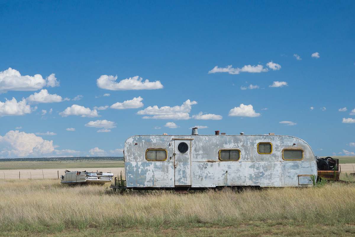encino gray metal travel camper on grass land under blue and white cloudy skies at daytime caravan